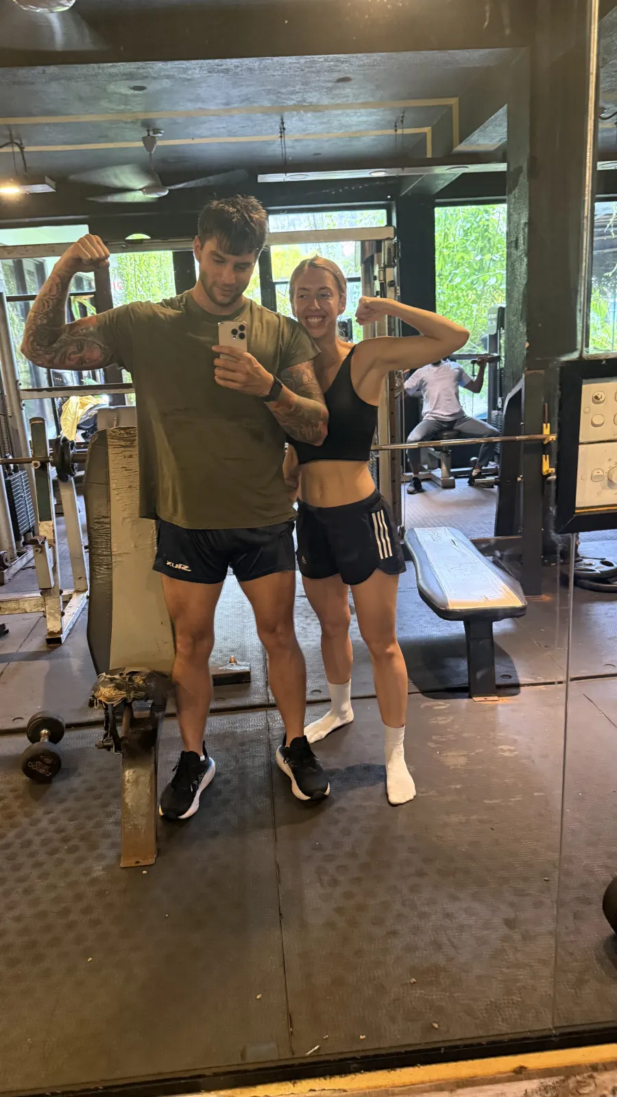 Los dos sacando bíceps frente al espejo del gimnasio.