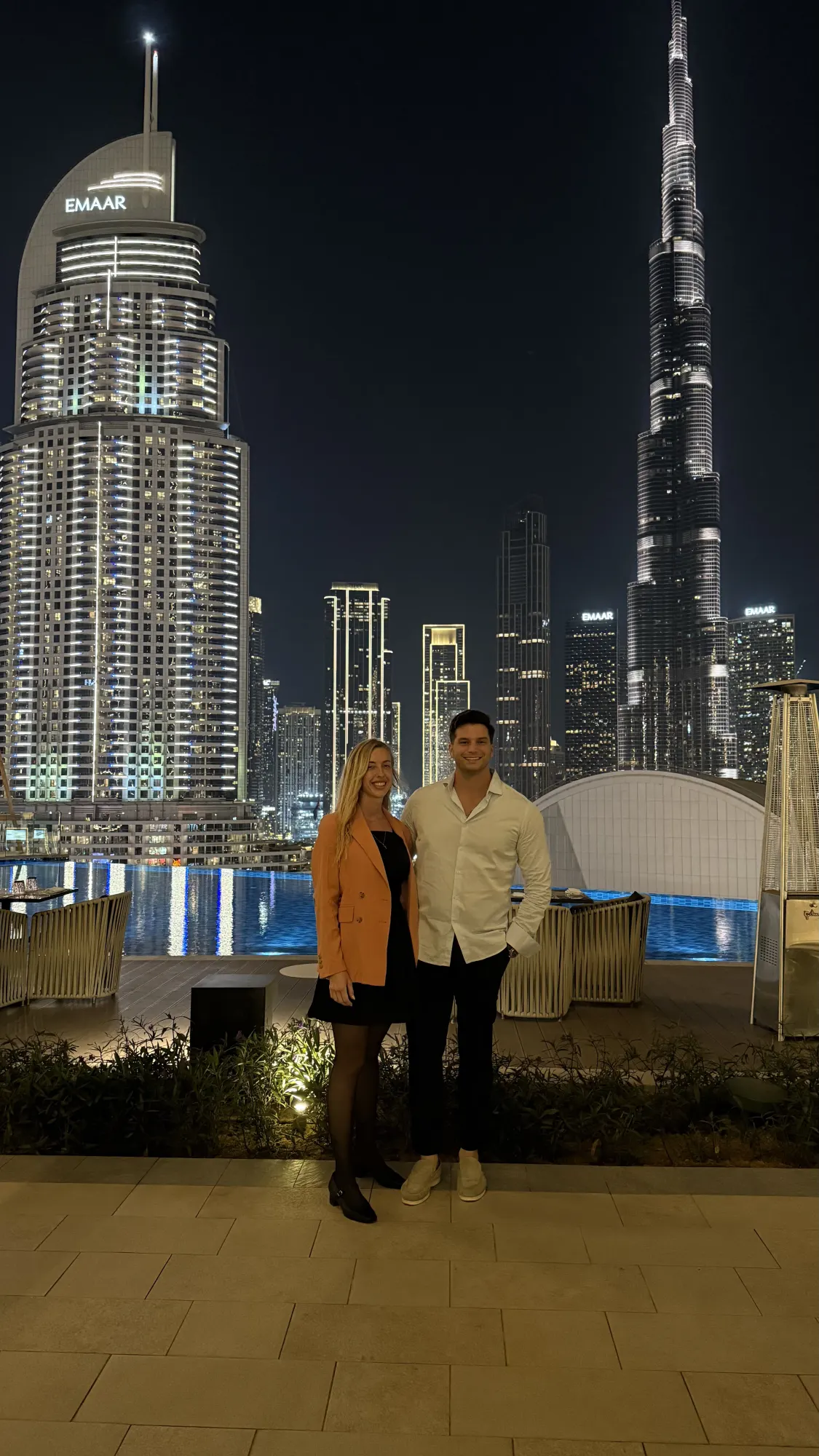 Los dos de noche en una terraza de Dubái, con el Burj Khalifa detrás.